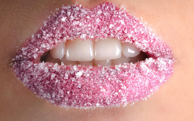 Close-up of lips covered in pink sugar crystals, showcasing creative lip styling often seen in beauty editorials