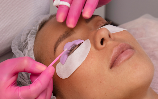 Close-up of freshly extended lashes being gently brushed with a spoolie