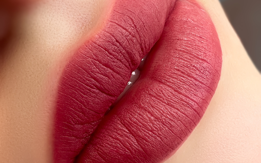 An extreme close-up of lips with a vibrant, matte, deep red color