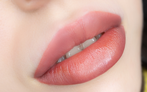 Close-up of freshly tattooed lips appearing bold, bright, and swollen