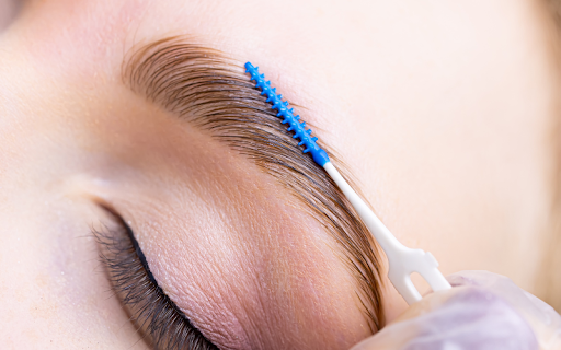 Aesthetician performing eyebrow waxing and tinting